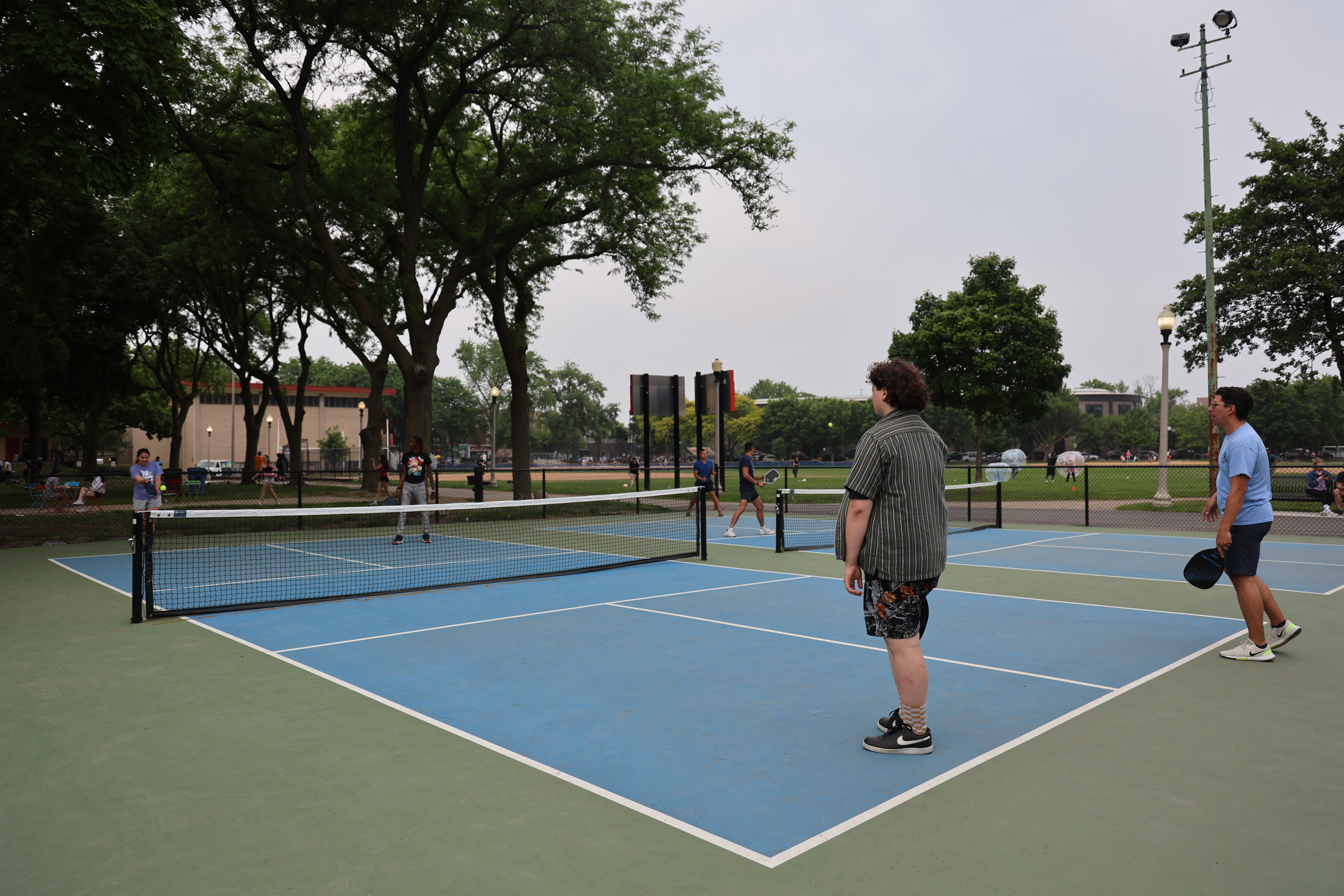 People playing pickleball on a blue and green court.